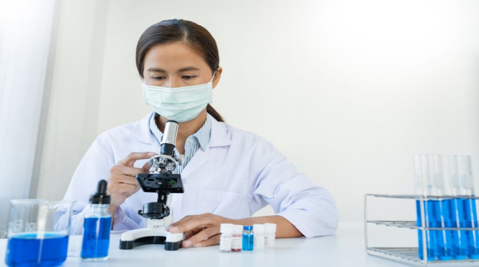 WOMEN LOOKING THROUGH A MICROSCOPE IN A LABORATORY